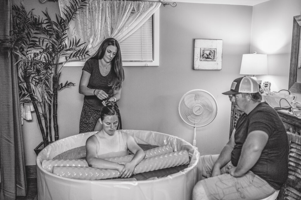 a woman is in a birth tub working through contractions